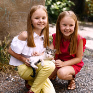 Девочки играют с котёнком на фоне зелени