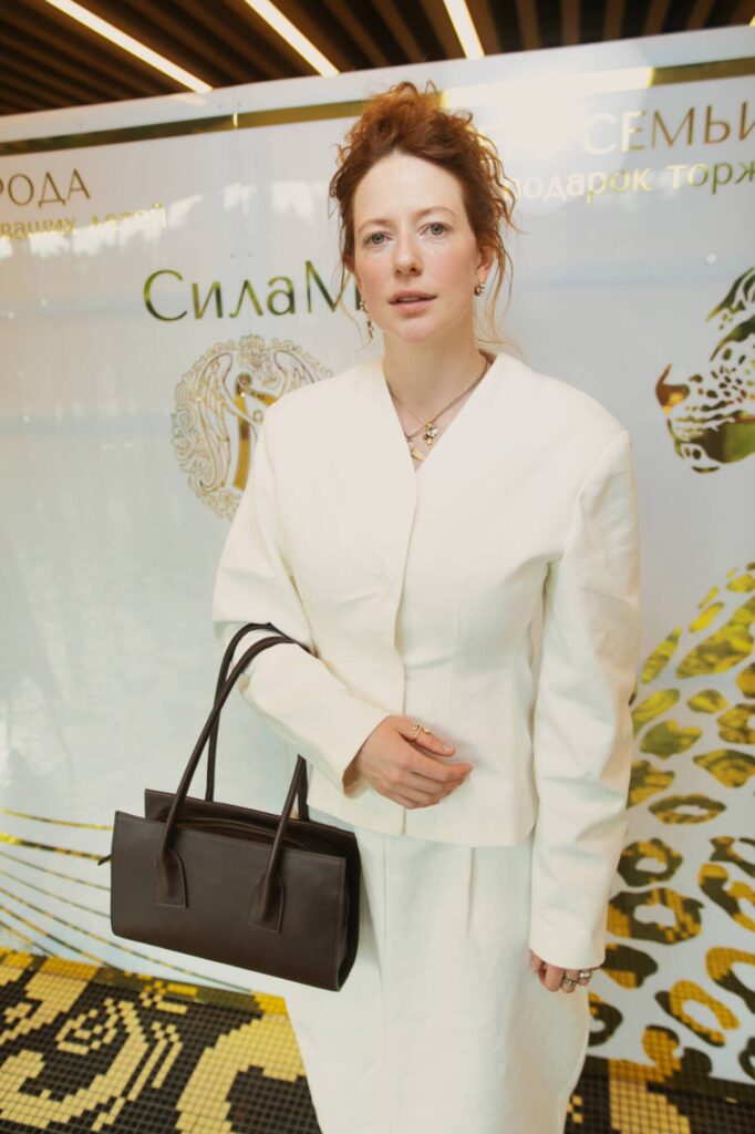 Стильный портрет девушки на фоне брендированной стены на официальном мероприятии