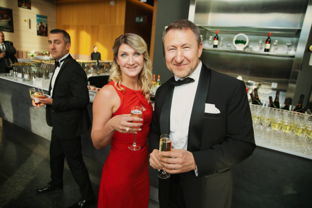 Пара в элегантных костюмах с бокалами шампанского на официальном приеме