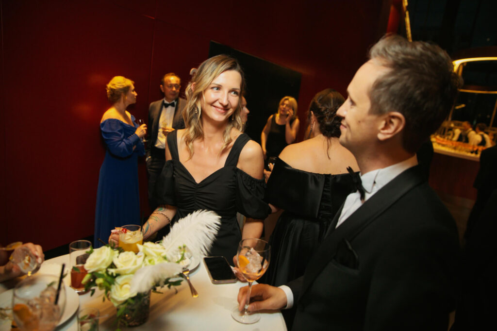 Мужчина и женщина в элегантных нарядах беседуют на светском мероприятии