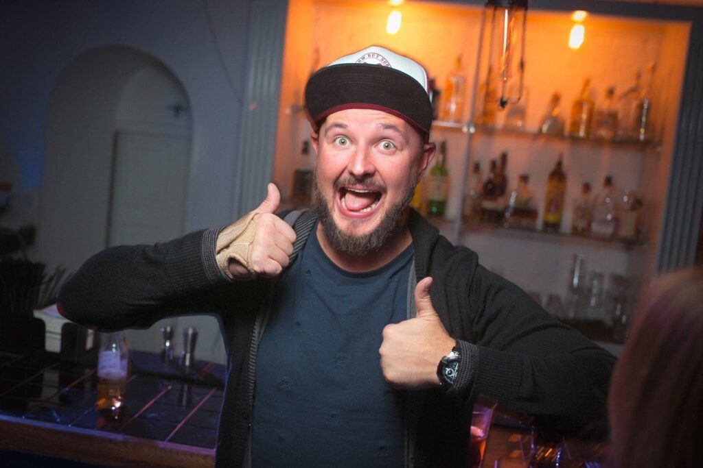 Веселый мужчина с поднятыми большими пальцами на вечеринке