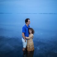 Отец и дочь в воде на фоне голубого горизонта