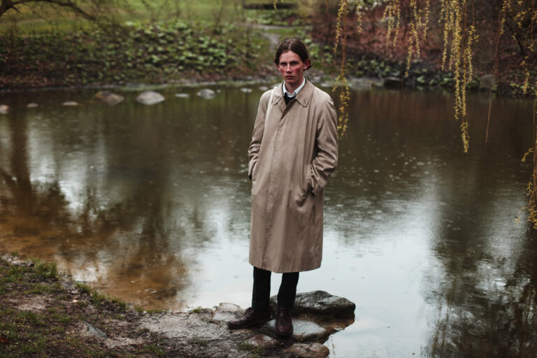 Стоит в воде пруда в тренче