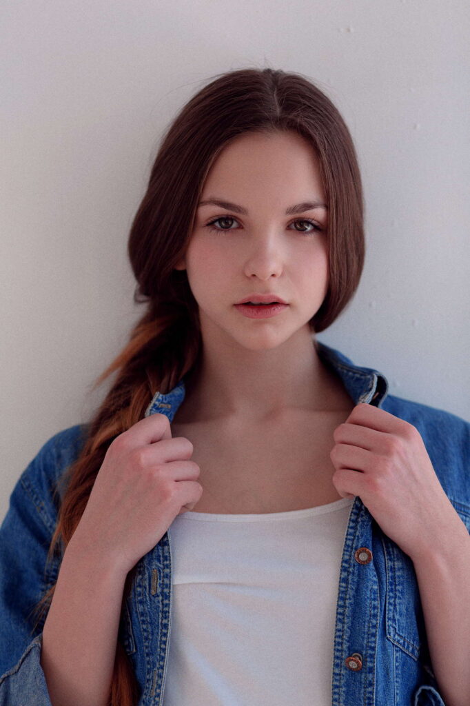 Девушка в джинсовой куртке на светлом фоне