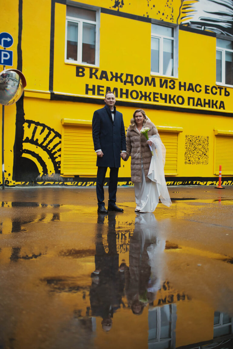 Пара у жёлтой стены с отражением в луже