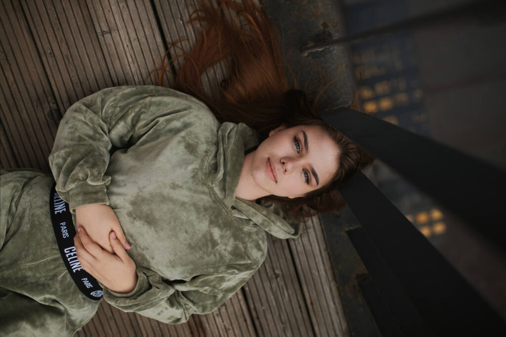 Девушка в зелёном костюме лежит на деревянном настиле